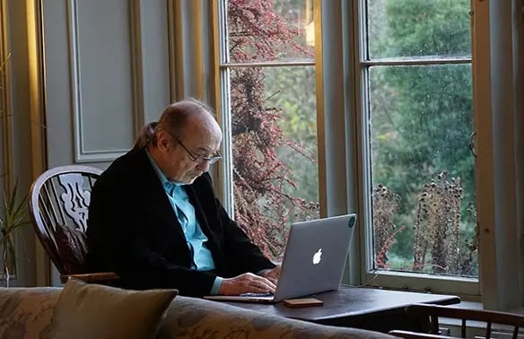 Man in a black suit jacket using senior living software on a laptop